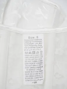 White lace corset detail showing size S tag and 100% polyamide material care instructions.