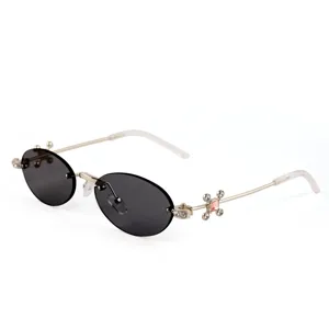 Rimless oval sunglasses for women, metal frame with rhinestones and cross detail, black lenses.
