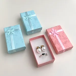 Scatole regalo chic rosa e azzurre con fiocco, perfette per confezionare gioielli con eleganza.