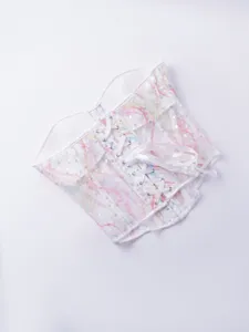 Gros plan d'un corset blanc transparent en résille, orné de sequins colorés et d'un laçage avant.