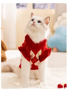 Vista detallada de un tierno gato con un suéter rojo de punto con patrón de rombos.