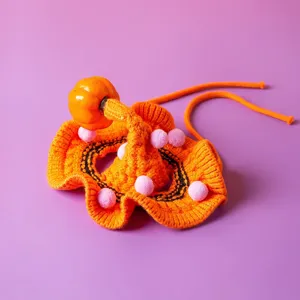 Cute Halloween pumpkin knitted pet collar detail, orange cat bib with pink pom poms accessory.