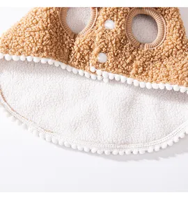 Detailed close-up view of brown fleece pet cape with white pom-pom trim and snap buttons.