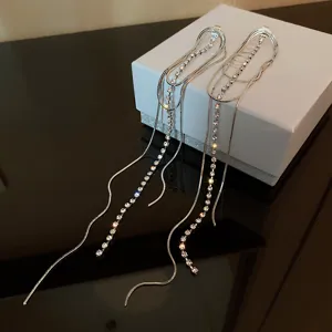 Detailed view of long silver rhinestone tassel earrings featuring elegant multi-strand snake chains.