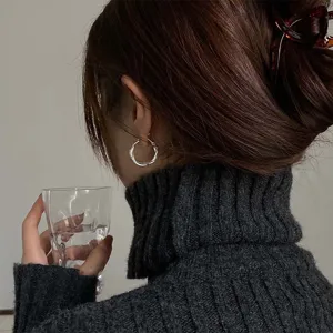 Vista dettagliata di eleganti orecchini a cerchio geometrici intrecciati in argento.
