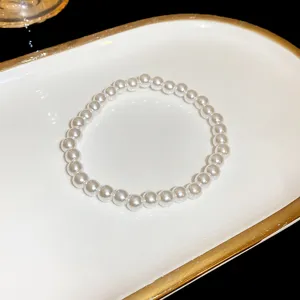 Exquisite pearl bracelet detail showing smooth round white beads on a elegant white and gold tray.
