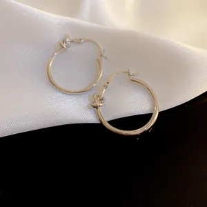 Dettaglio in primo piano di orecchini a cerchio in metallo argentato con nodo, eleganti.
