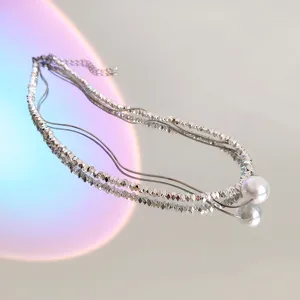Detailed shot of layered silver bead pearl necklace, minimalist clavicle chain design with pearl.