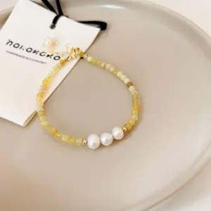 Detailed view of exquisite yellow gemstone beaded bracelet accented with three white pearls.