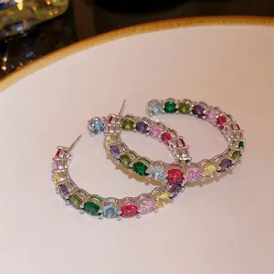 Orecchini a cerchio in metallo con zirconi colorati scatto di dettaglio con pietre multicolore.