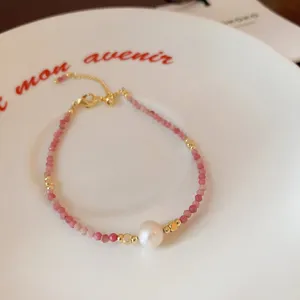 Detailed view of freshwater pearl and pink crystal beaded bracelet with gold tone metal parts.
