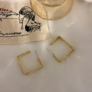 Nahaufnahme Detailansicht minimalistischer geometrischer quadratischer Ohrringe auf Stoff.