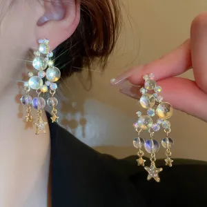 Close-up of sparkling crystal star tassel earrings, highlighting brilliant reflective facets.
