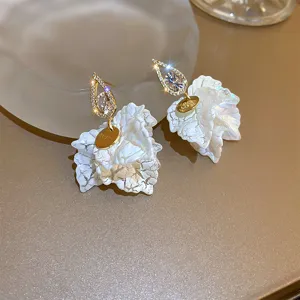 Detail view of chic teardrop zircon earrings with textured white flower petals and charm.