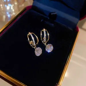 Exquisite detailed shot of gold geometric zircon tassel earrings in luxury jewelry box.