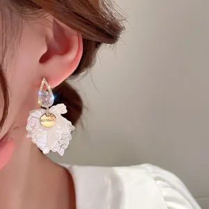 Close-up detail of elegant white petal zircon dangle earrings featuring a shiny engraved round tag.