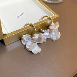 Close-up detail of sweet pearl petal hoop earrings featuring elegant gold electroplating.