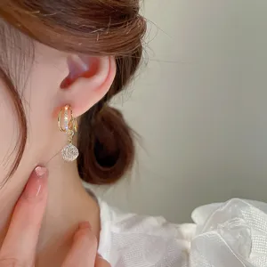 Close-up detail of elegant zircon geometric tassel stud earrings worn on the ear model.