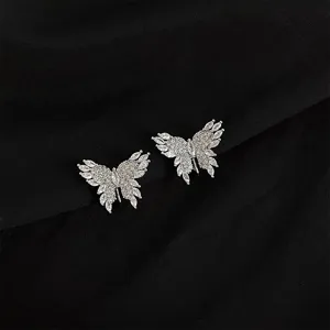 Close-up detail of sparkling zirconia butterfly ear clips, elegant silver tone metal design.