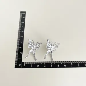 Detail view of silver metal hollow butterfly earrings with size ruler for clear dimension display.