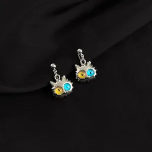 Close-up of quirky punk cat earrings featuring dual-color resin eyes and metallic finish.