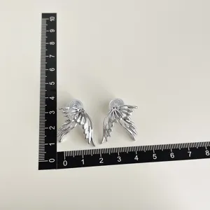 Silver wing clip-on earrings detail shot showcasing size scale and unique metal design.