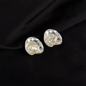 Close-up detail of irregular shell-shaped ear clips with pearlescent and gold flake accents.