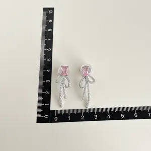 Detail view of pink crystal bow-knot clip-on earrings with shimmering rhinestones.