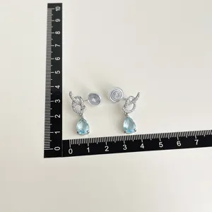 Detail view of non-pierced clip-on earrings with crystal drop and size measurement ruler.