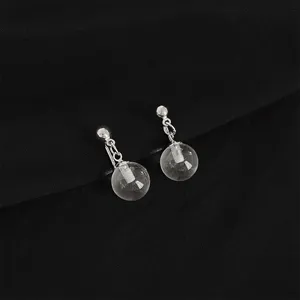 Close-up detail of transparent glass ball drop earrings with silver metal chain clip.