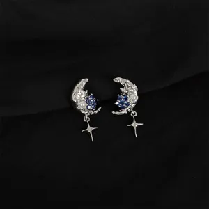 Detailed close-up of silver moon and star earrings featuring sparkling blue crystals and pearls.