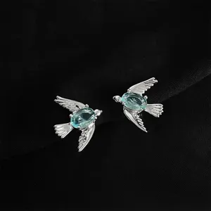 Exquisite silver-tone bird earrings featuring sparkling blue oval gemstone accents for women.