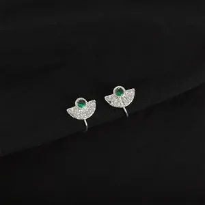 Close-up detail of silver clip-on earrings with green gem and fan-shaped textured design.
