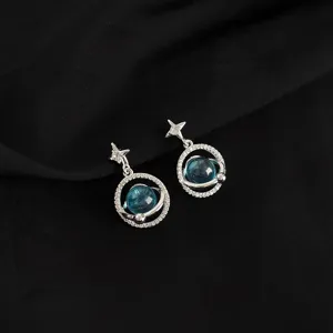 Close-up detail shot of celestial planet earrings with sparkling crystal stones and silver finish.
