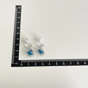 Detailed view of blue planet clip-on earrings with metallic rings and shimmering star charms.