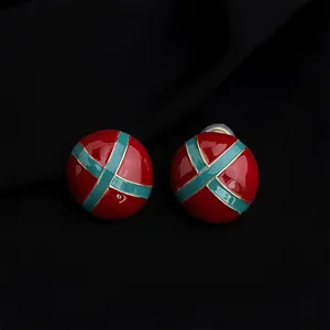 Close-up detail of vintage retro burgundy and green enamel clip-on earrings with gold trim.