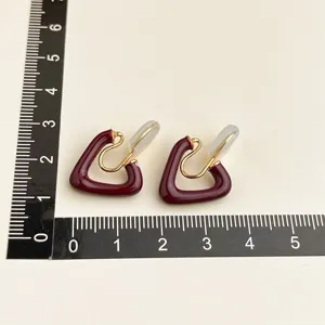 Detail view of wine red triangle clip-on earrings with gold hardware and measurement ruler.
