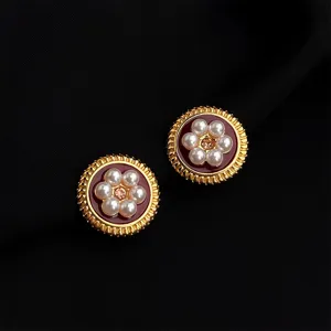 Close-up detail of retro wine red enamel pearl clip-on earrings with gold-tone finish.