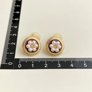 Detailed view of vintage burgundy oil-drop pearl clip-on earrings with size ruler.