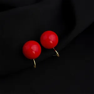 Close-up of wine red minimalist round clip-on earrings with gold finish, elegant detail shot.