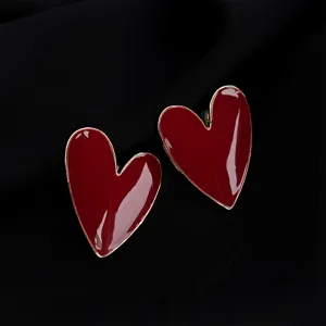 Close-up detail of glossy dark red heart enamel clip-on earrings with elegant gold trim.
