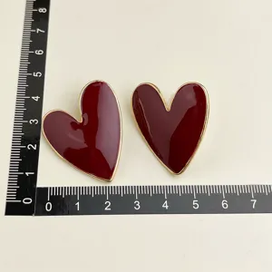 Detailed view of vintage wine red heart shaped earrings with metal trim and size reference ruler.