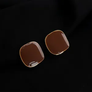 Detail shot of retro dark red geometric enamel clip-on earrings with gold-plated trim.