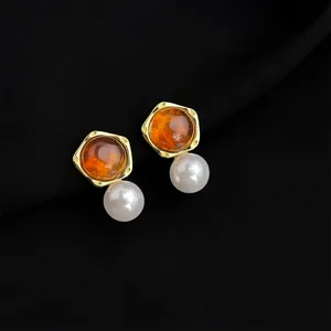 Close up detail of retro amber and pearl drop earrings, elegant gold-plated geometric design jewelry.