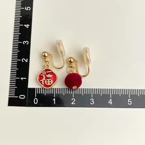 Vintage red enamel blessing character and plush pom-pom clip-on earrings for women.