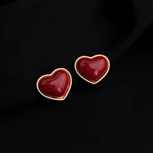 Close-up view of elegant burgundy red heart earrings with gold rim, retro jewelry design.