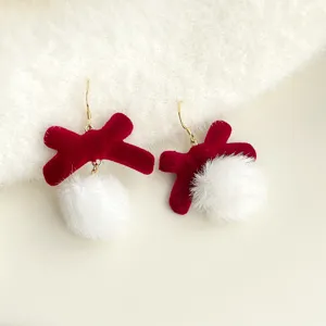 Nahaufnahme der süßen roten Beflockungs-Schleife und weißen Bommel-Ohrringe, weiche Textur.