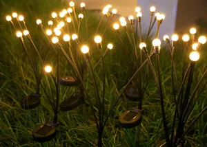 Detail van solar vuurvlieg tuinlamp, warme LED lampjes sfeervol op het gras.