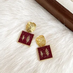 Detailaufnahme von vintage roten geometrischen Ohrringen mit Goldfedern und Glitzer.