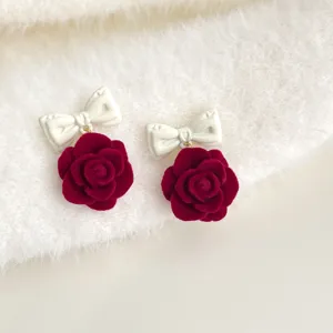 Nahaufnahme von roten beflockten Rosenohren mit weißen Schleifen, elegante Herbstdetails.